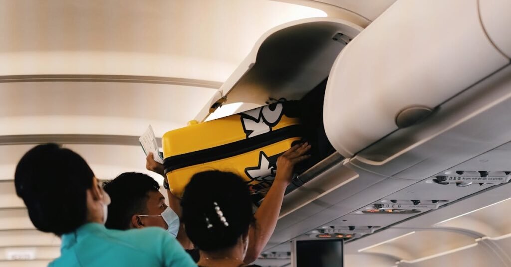 Passengers placing a yellow suitcase in the overhead bin of an airplane cabin. Interior with crew assistance.