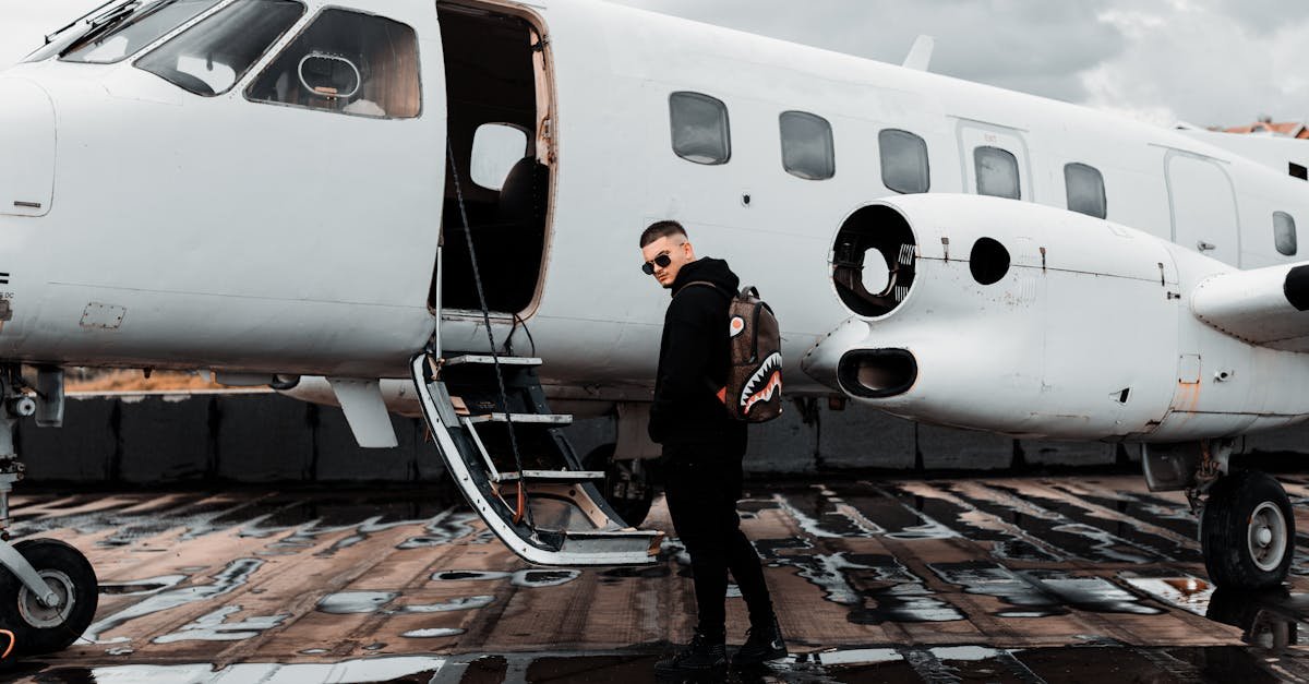 A man with a backpack boards a private jet on a wet airport tarmac in Tirana, Albania.