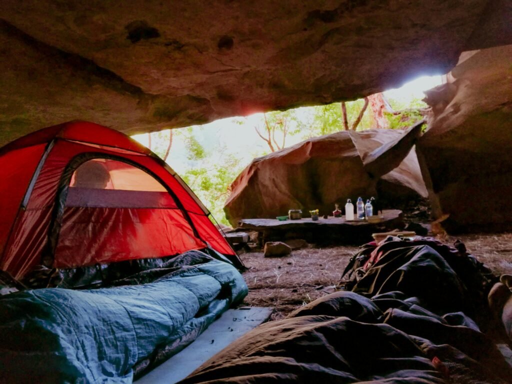 Explore the serenity of cave camping with a red tent in a natural setting, capturing relaxation and adventure.