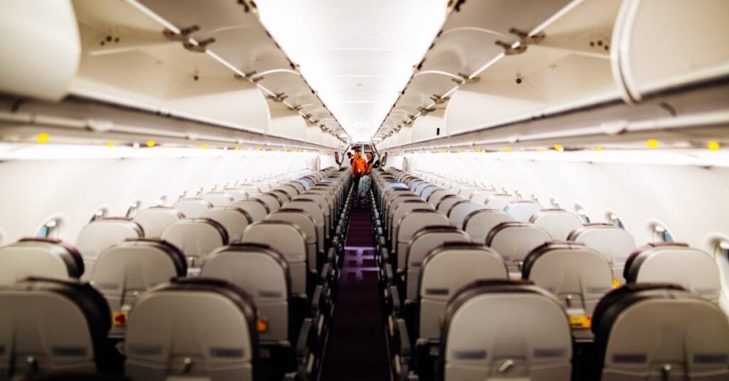 View of an empty airplane interior with aisle seats and overhead bins.