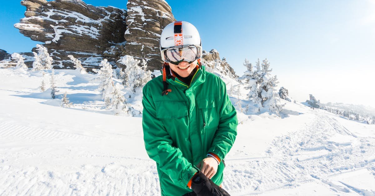 Smiling person in winter gear enjoying snowy outdoors by impressive rock formations.