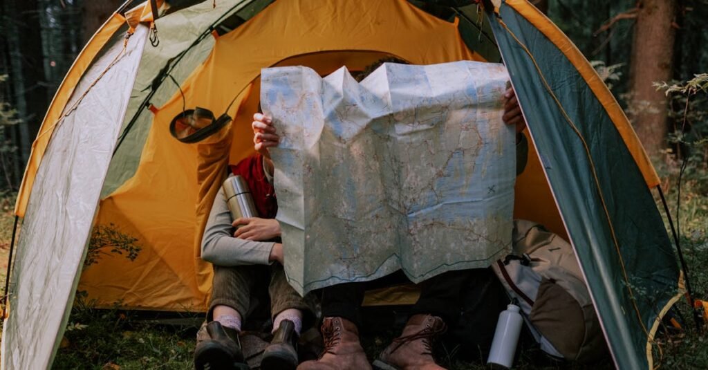 Two people enjoy a camping trip, examining a map inside a tent surrounded by nature.