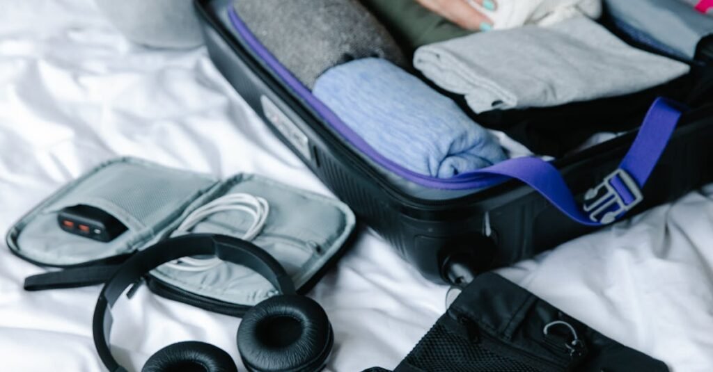 Person organizing suitcase with clothes and toiletries on bed, preparing for travel.